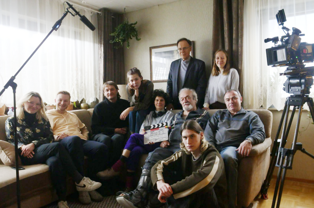 wega film - eine Runde von Menschen sitz am Sofa und sie schauen in die Kamera